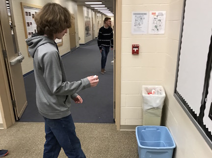 Sophomore Ethan McNanny disposes of paper in the recycling bin in the Orchestra room, which the Recycling Club clears three times a week. Photo by Ethan OSullivan.