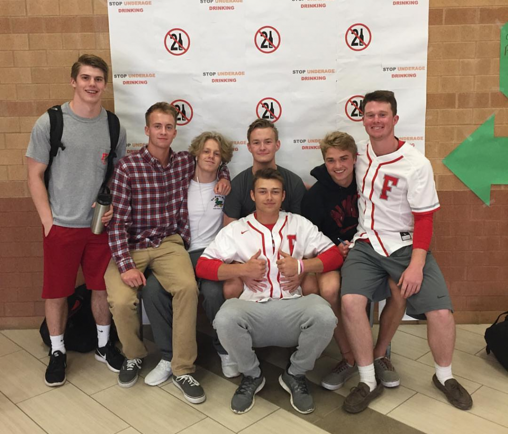 Senior Palmer Rauschenbach poses with his friends in front of the Underage Drinking Awareness poster in the cafeteria. Photo used with permission of Palmer Rauschenbach.