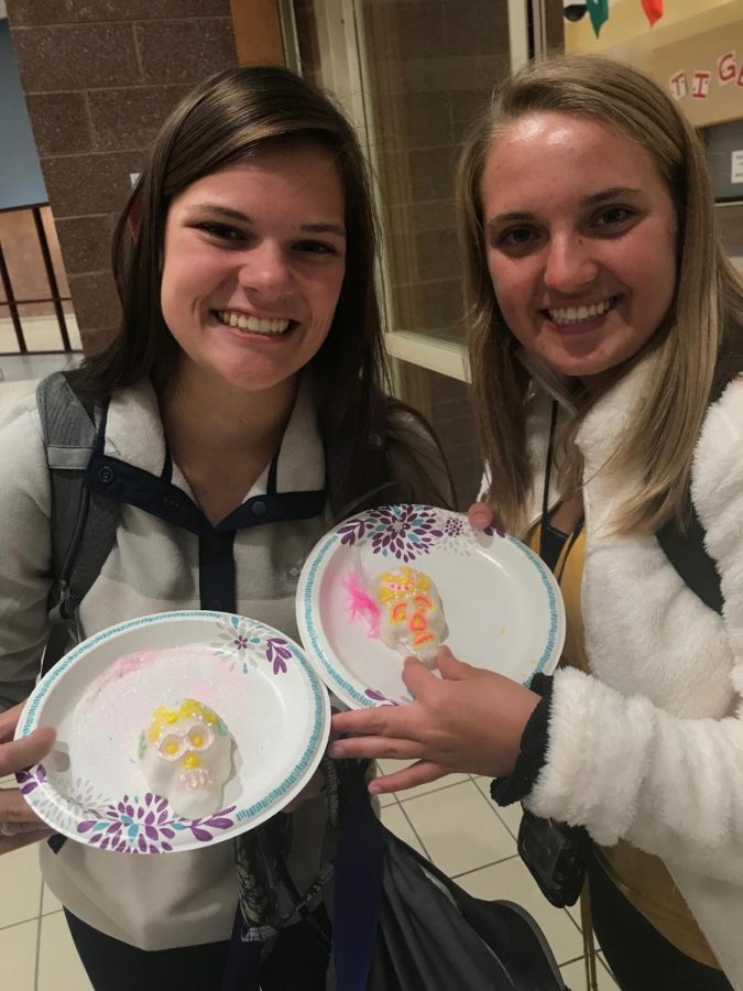 Junior Alexis Castellani and junior Candace Smallwood show off their skull candies that they decorated for the Mexican holiday Día de Muertos at the cafeteria for Spanish club during October.