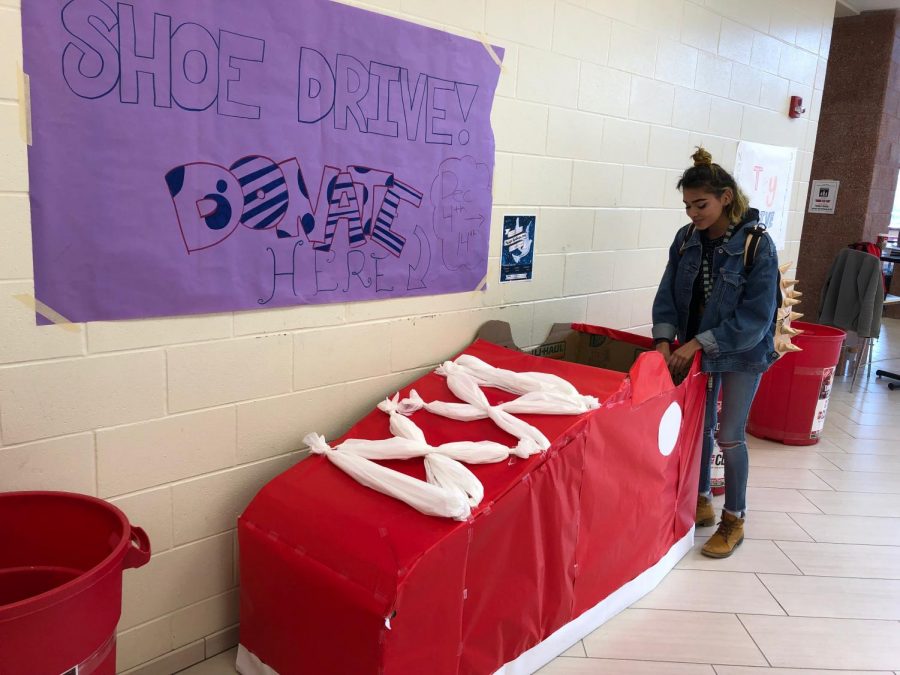Senior Julia Garrison donates a pair of shoes at the CCA entrance in a “shoe box” made by students in Students in Action.