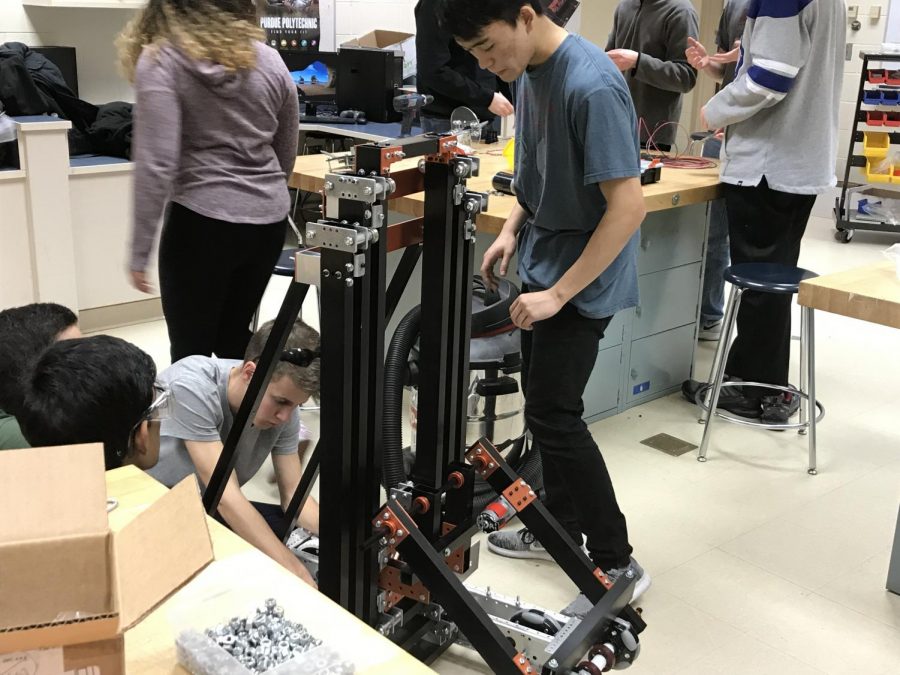 Tables around the competition robot are covered with parts as freshman Truman Mohr and junior Yuya Sawamoto work on their bot on Feb. 13.