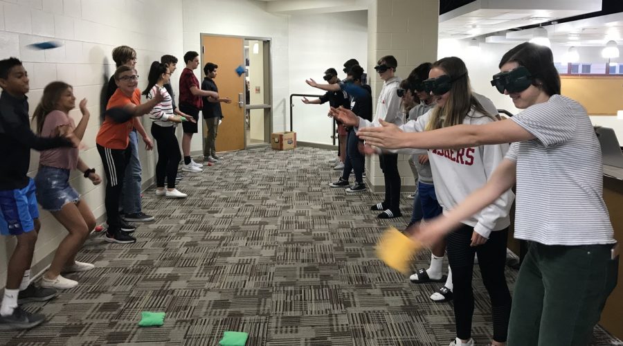 Students wearing vision altering goggles attempt to throw bean bags to their partners. 