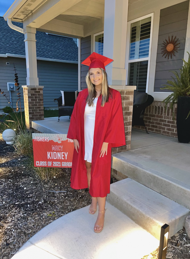 Kidney poses for a photo with her cap and gown next to her sign outside her house on May 10 for the senior video. 