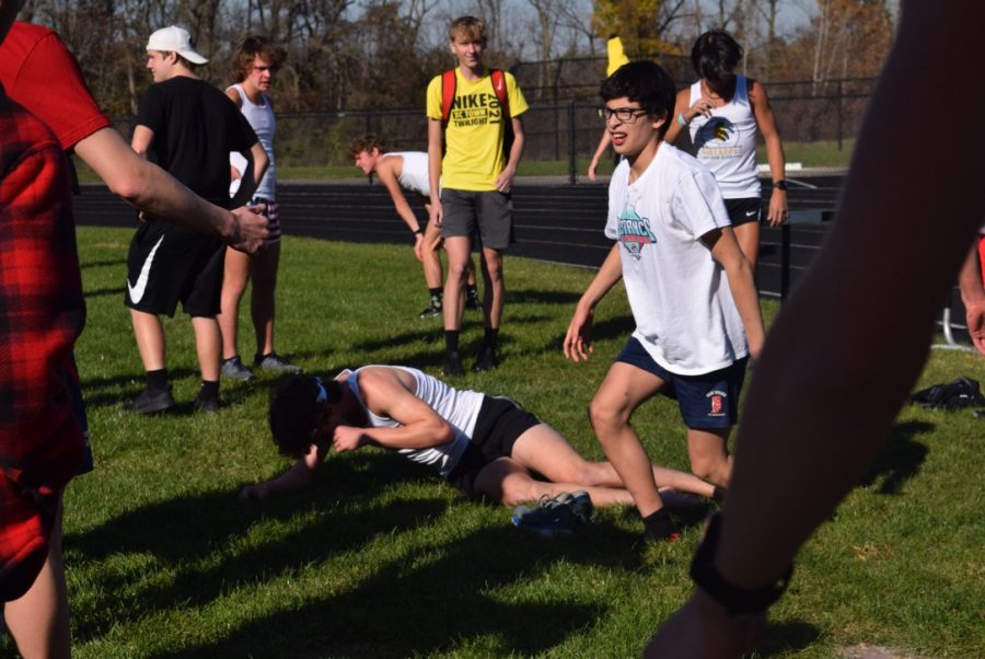 Junior Braden Hoosier-Hartman lies on the ground after he finishes his Milk Mile while freshman Eduardo Sanchez walks through the field after his race.
