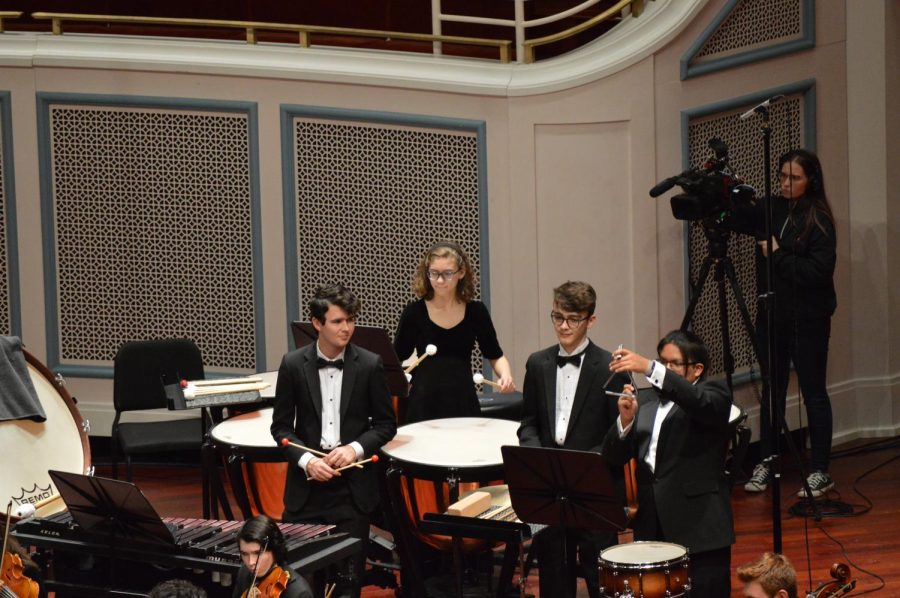 Freshman Kate Armey concentrates on the timpani, while senior Aiden Huggles watched juniors Matthew Johnston and Bert Quay accompany the Symphony Orchestra. 2021 Fishers graduate Makayla Hansen is seen filming the performance. The Showcase occurred on April 26th.