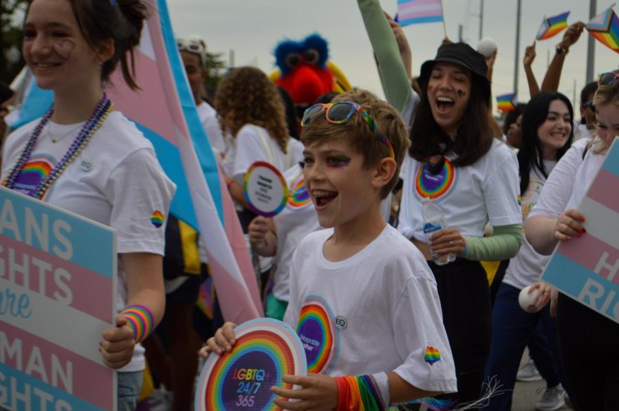 A preteen laughs and cheers while marching with adults carrying transgender pride flags. “I really like how everyone felt comfortable expressing themselves and…displaying whatever flag represented them,” senior Ari Goldman said.
