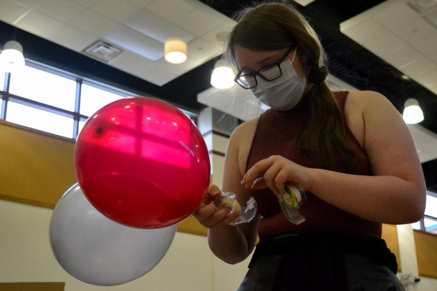 Senior Susan Farlow tapes together balloons for the balloon arch. The window decorating event took place Sept. 11.