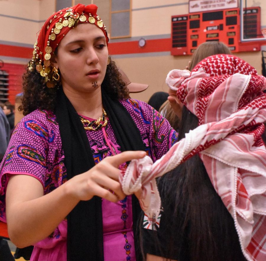 Senior Barthenia Abdelshahid ties a headscarf for an attendee of the International Fair. The International Fair took place on Feb. 24 at Fishers High School.
