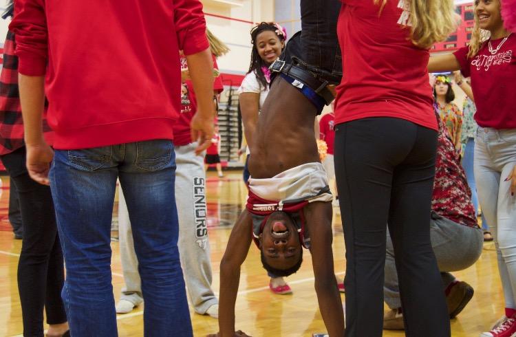 Students help Senior LeShawn Bocot hold a handstand in preparation for the mannequin challenge on Nov. 19 in the main gym. Photo by Hannah Nguyen. 