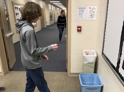 Sophomore Ethan McNanny disposes of paper in the recycling bin in the Orchestra room, which the Recycling Club clears three times a week. Photo by Ethan O'Sullivan.