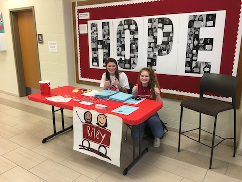 My job is to promote getting people to the dance marathon. I;m trying to get people aware of what Riley can do for the kids. sophomore Emma Gabbard said. Gabbard and Kristi Gordon promote Riley in front of a banner depicting the word Hope, created by junior Abby Rollison. Photo by Lia Benvenutti. 