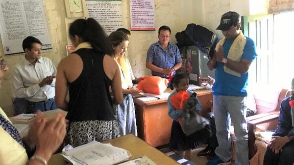 Juniors Liza Pradhan and Maddie Butler distribute donated supplies like clothes and books to school children in Nepal in July 2017. Photo used with permission of Rojal Pradhan.