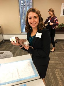 Senior Elinor Carmona holds a simulator baby during an interview at the University of Cincinnatis College of Nursing Nov. 2. After the interview, students had the opportunity to demonstrate their skills by delivering simulator babies and taking samples from an umbilical cord. 