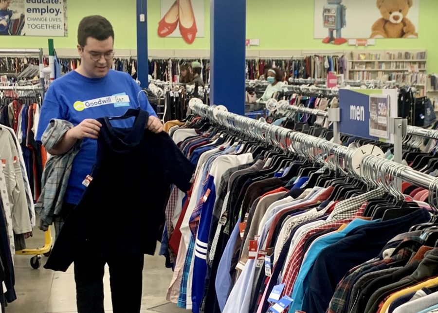 Senior Ben Crowe rehangs a shirt that had fallen off its hanger during his shift at Goodwill in Fishers Station on April 22.