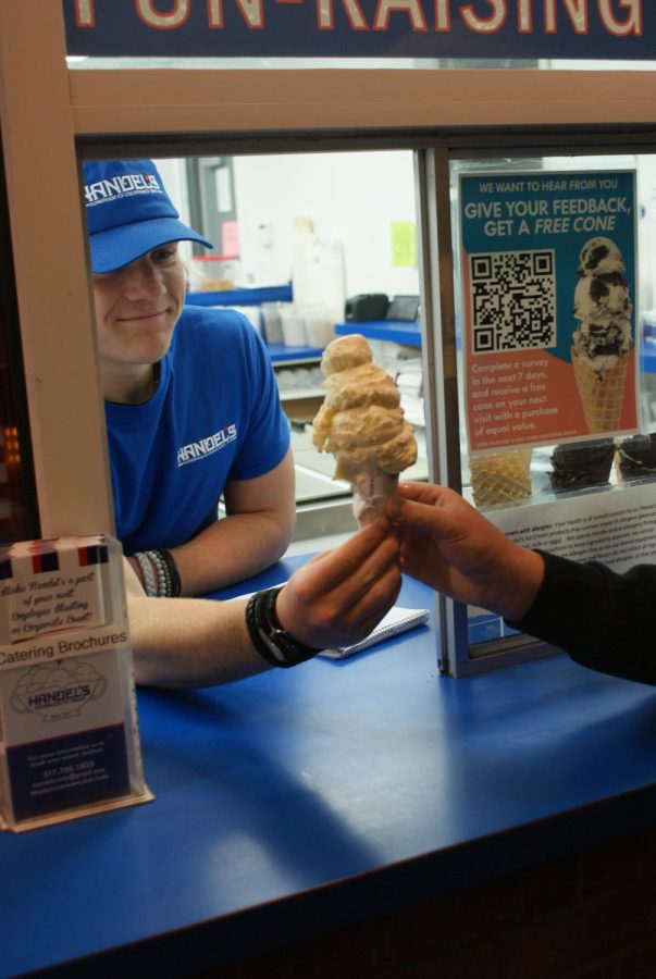 During his shift on April 13, sophomore Kyan Cassidy serves a customer a medium cone of cake batter ice cream at Handel’s Homemade Ice Cream Fishers. “My favorite thing about working at Handel’s is getting to work with the great employees that work here,” Cassidy said. 