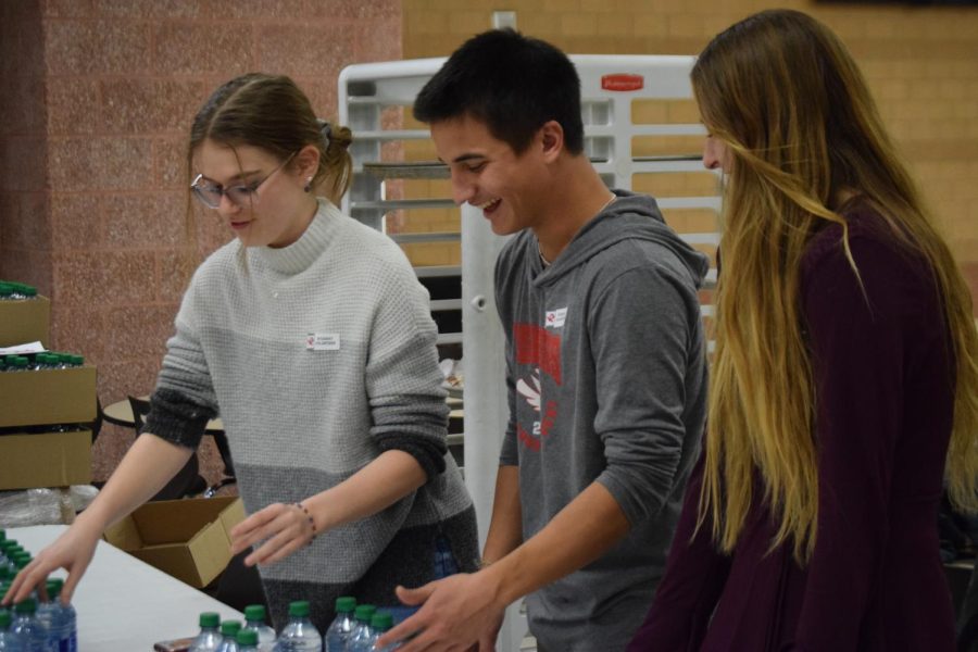 (Left to right) Seniors Sylvia Martin, Logan Aribe and Annalise Roach pass out cookies and water to parents as they walk around the school. Eighth-grade parent night took place Feb. 1.