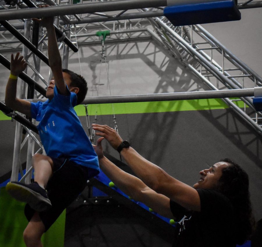 Gil assists Gavin Settecasi, a third-grader at Sand Creek Elementary, with holding on to an obstacle at the Pro Ninja Clinic. The Pro Ninja Clinic took place on Feb. 25 at Ultimate Ninjas Indianapolis.