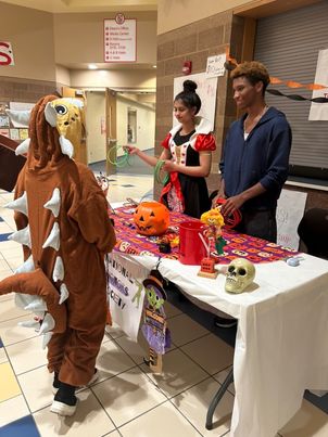 Senior Vani Sharma and junior Jayden Rucker as they explain a table game for the National Honor Society’s booth to a visitor.