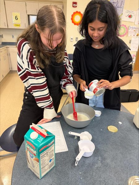 Junior Lyla Rodenberger and Rheya Ravishankar,  mix ingredients to make Pina Colada Tres Leches during a baking club meeting on Nov. 21.