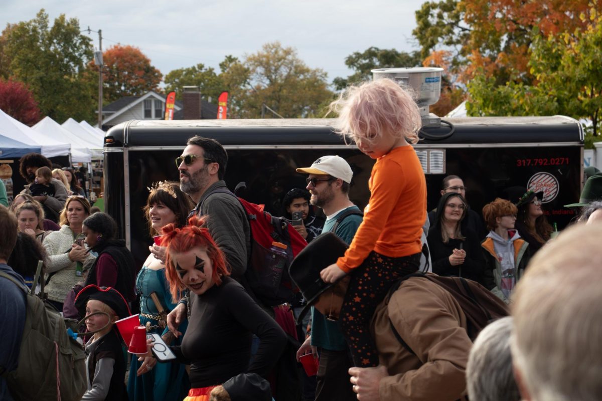 A child overlooking the Irvington Halloween Festival’s Parade above. Hundreds surround him to experience it together. Photo by Mel Lister.