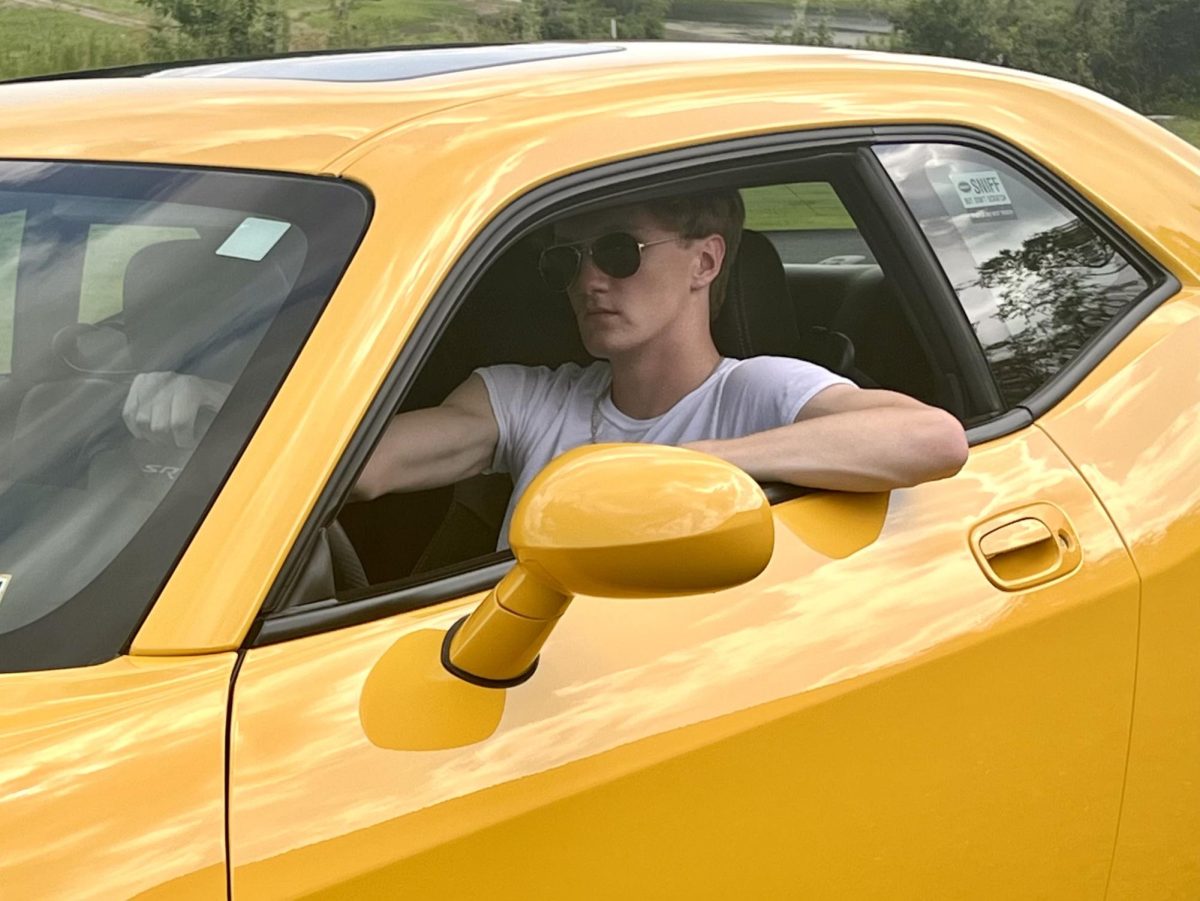 Nicholas Riley, a senior, posing in his grandpa’s 2010 Dodge Challenger SRT for his senior photos. He plans on buying it in the future and chose it as a prop since he grew up with it. Photo used with permission of Heather Riley.