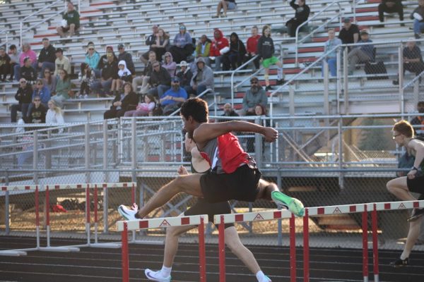 Senior Joel Leo Prakash jumps over a hurdle at Fishers High School on March 9 for the Men’s 110m Hurdles. People in the crowd watch his maneuver.