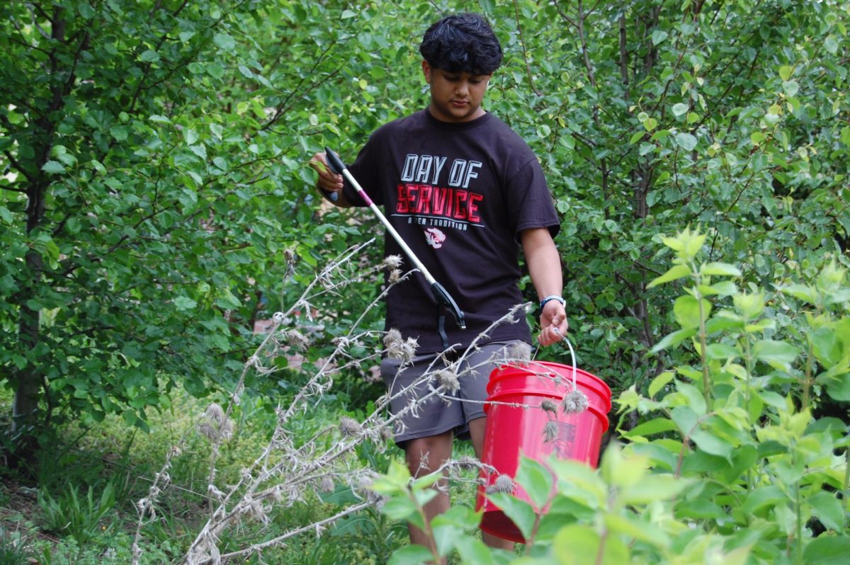 Sophomore Srihari Ajay picks up trash at Hamilton Proper Park for Day of Service on Friday, April 24. He held a red bucket to put the trash in. “I think this project is pretty impactful because I feel like a lot of people litter every day,” senior Diego Bermudez, a volunteer cleaning up the park said. “I like getting this park clean and making it accessible to everyone.” 