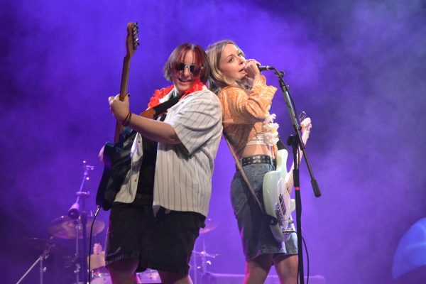 At the fourth annual Spring Thing concert fundraiser for the radio station WFYI, seniors Mica Jordan and Kylie Schwegman lean against each other as they perform with their band, Take Cover, on May 2. The concert had a beachy theme, with performers wearing leis and grass skirts.  